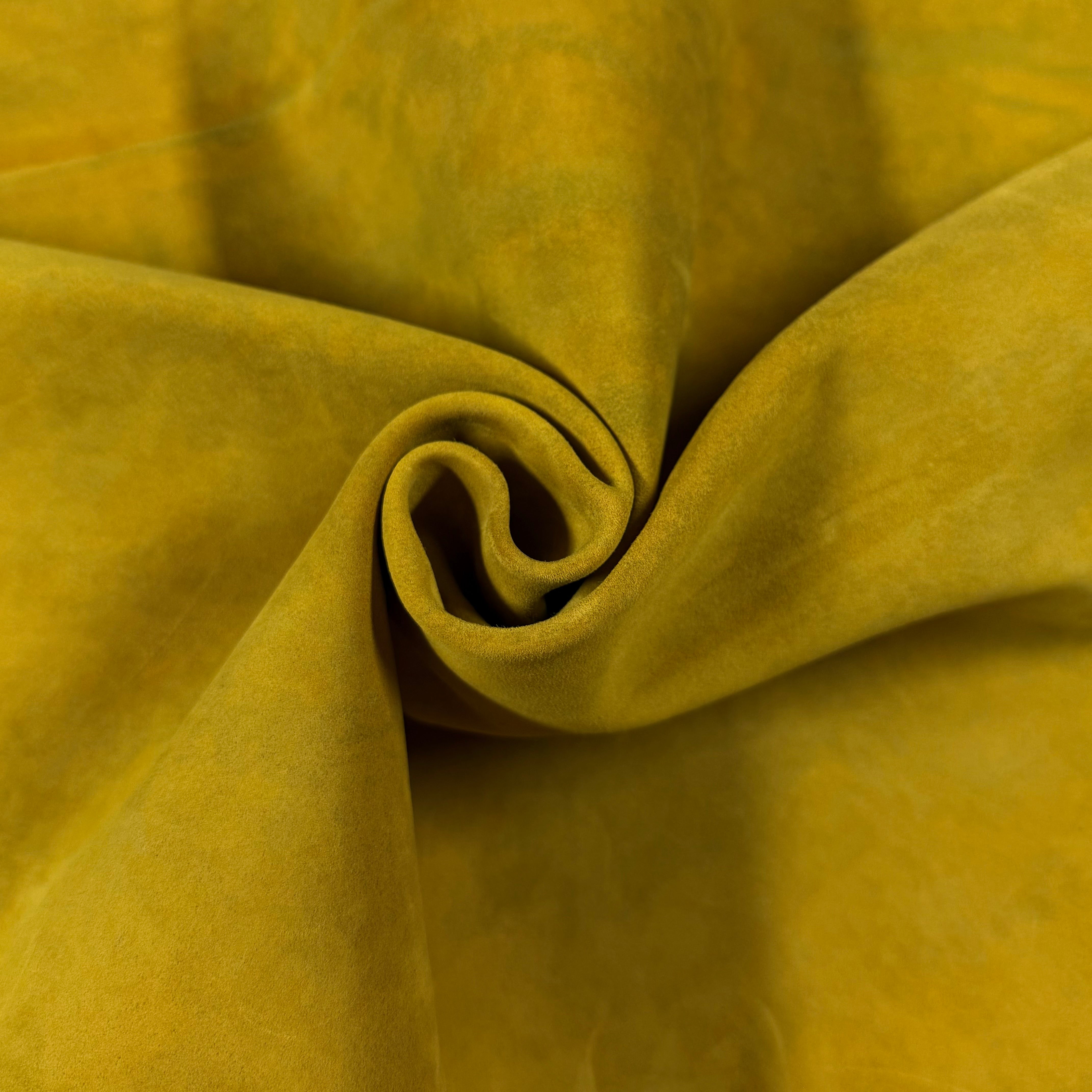 Close-up of a swirled piece of soft, mustard yellow Conceria Incas Italian Water Calf leather with a suede-like finish.