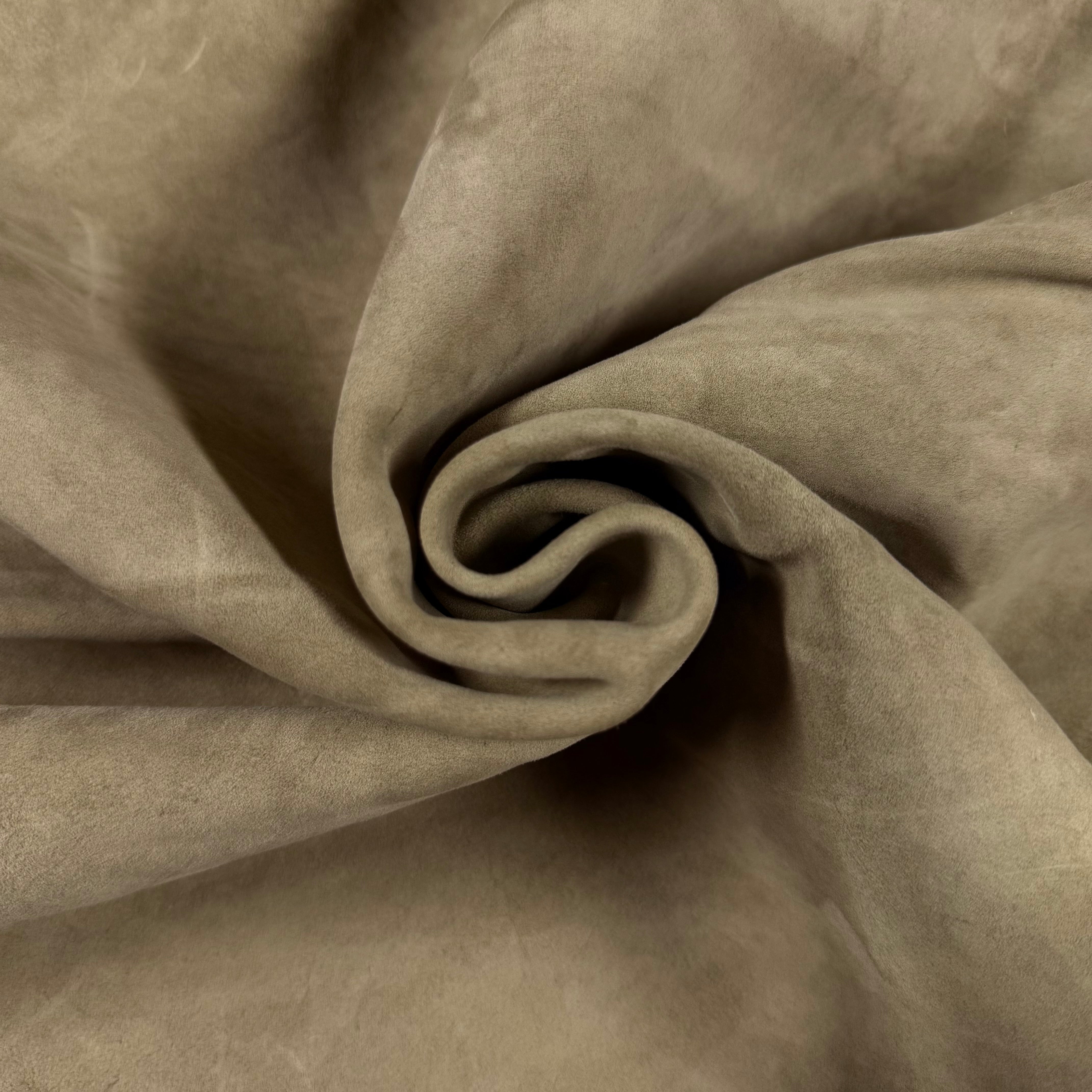 Close-up of a coiled piece of soft, suede-like Conceria Incas Italian Water Calf leather in a natural tan color.