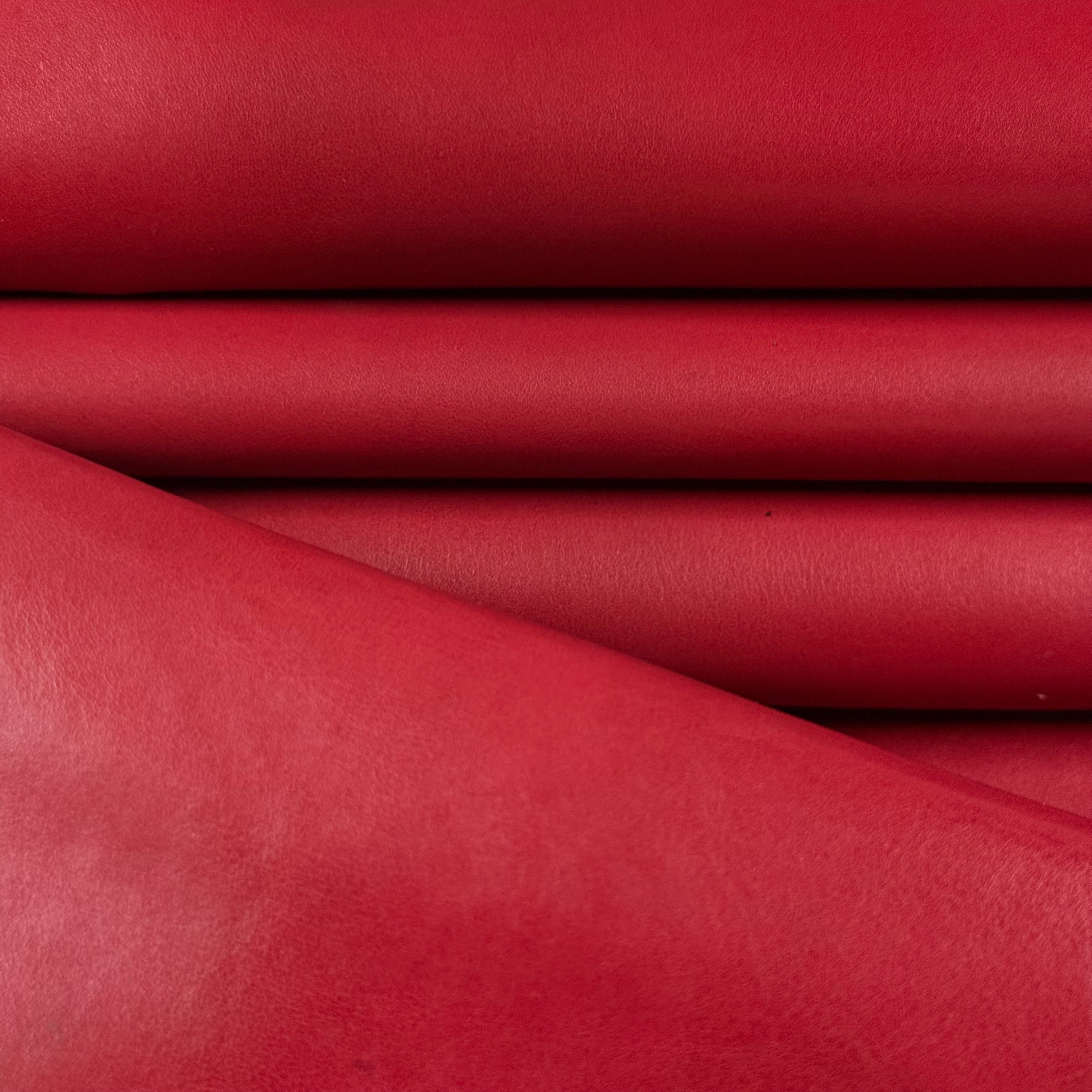 Smooth red vegetable-tanned baby calf leather, folded and stacked, showing its polished surface.