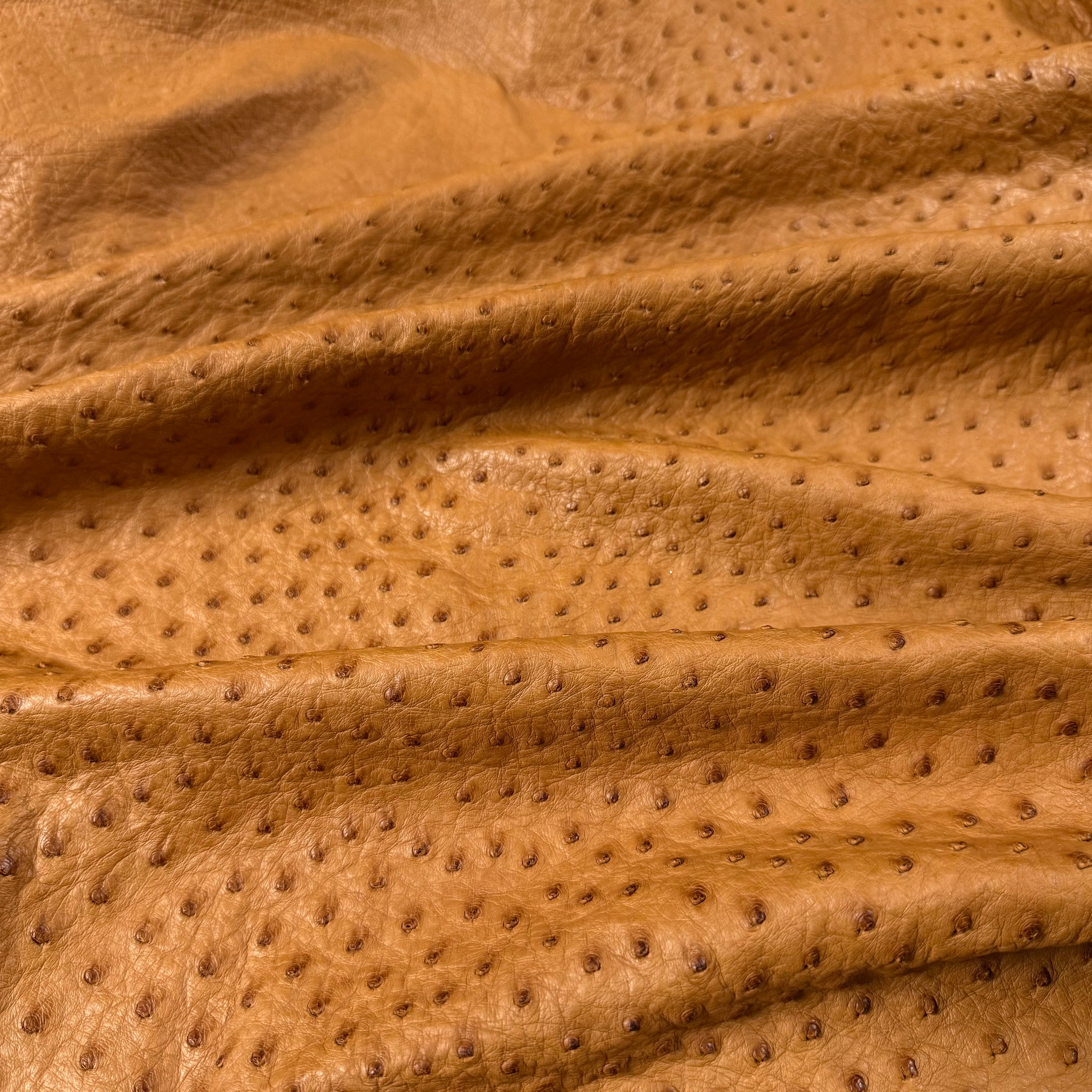 Close-up of a folded, tan full quill genuine ostrich leather hide with distinctive raised quill pattern.