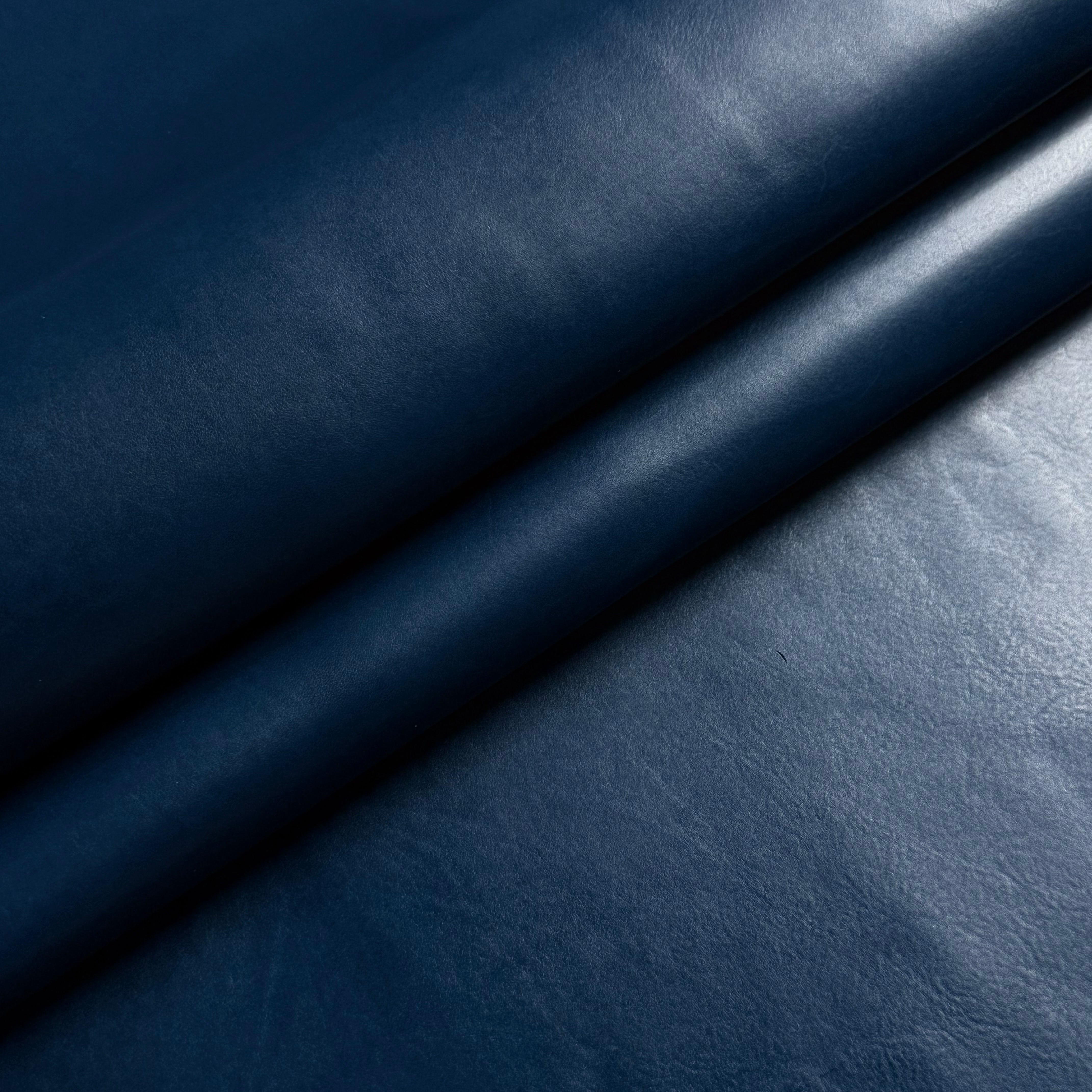Smooth navy blue vegetable-tanned baby calf leather with a polished aniline finish and subtle natural texture.