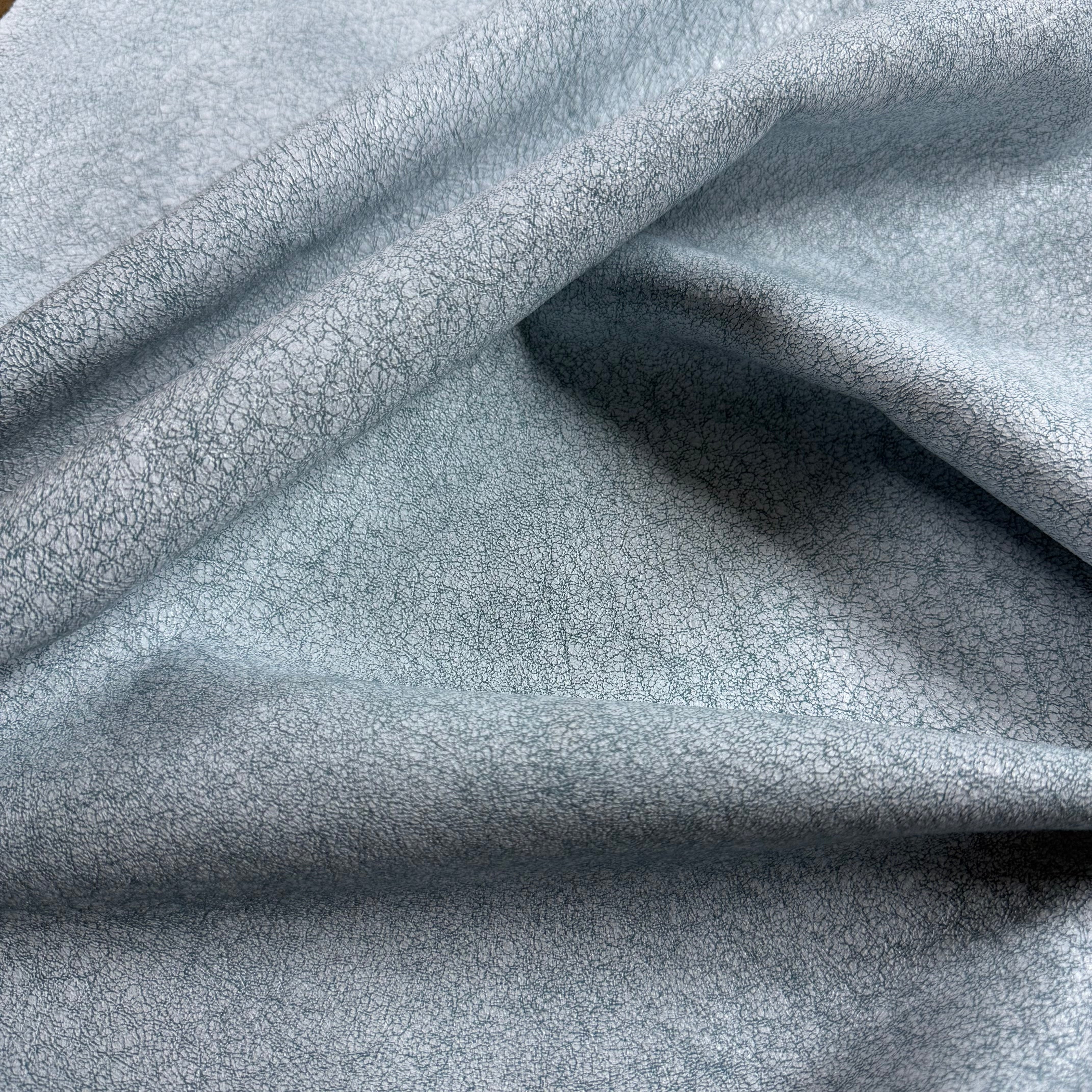 Light blue Crackle Leather fabric with a textured, distressed finish and soft, draped folds.