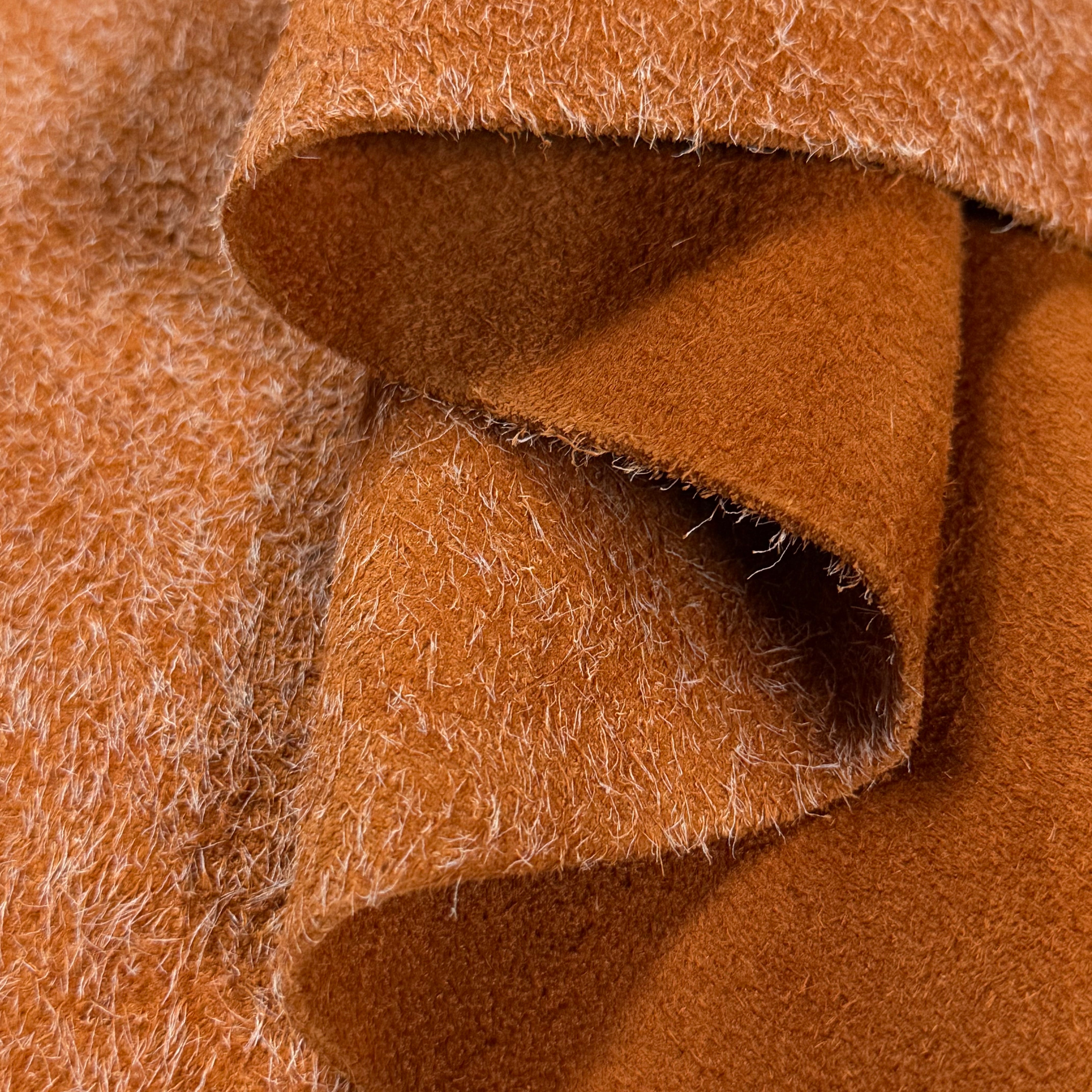 Close-up of a folded Hairy Calf Suede Bend in a rich brown color, showing its shaggy, textured surface.
