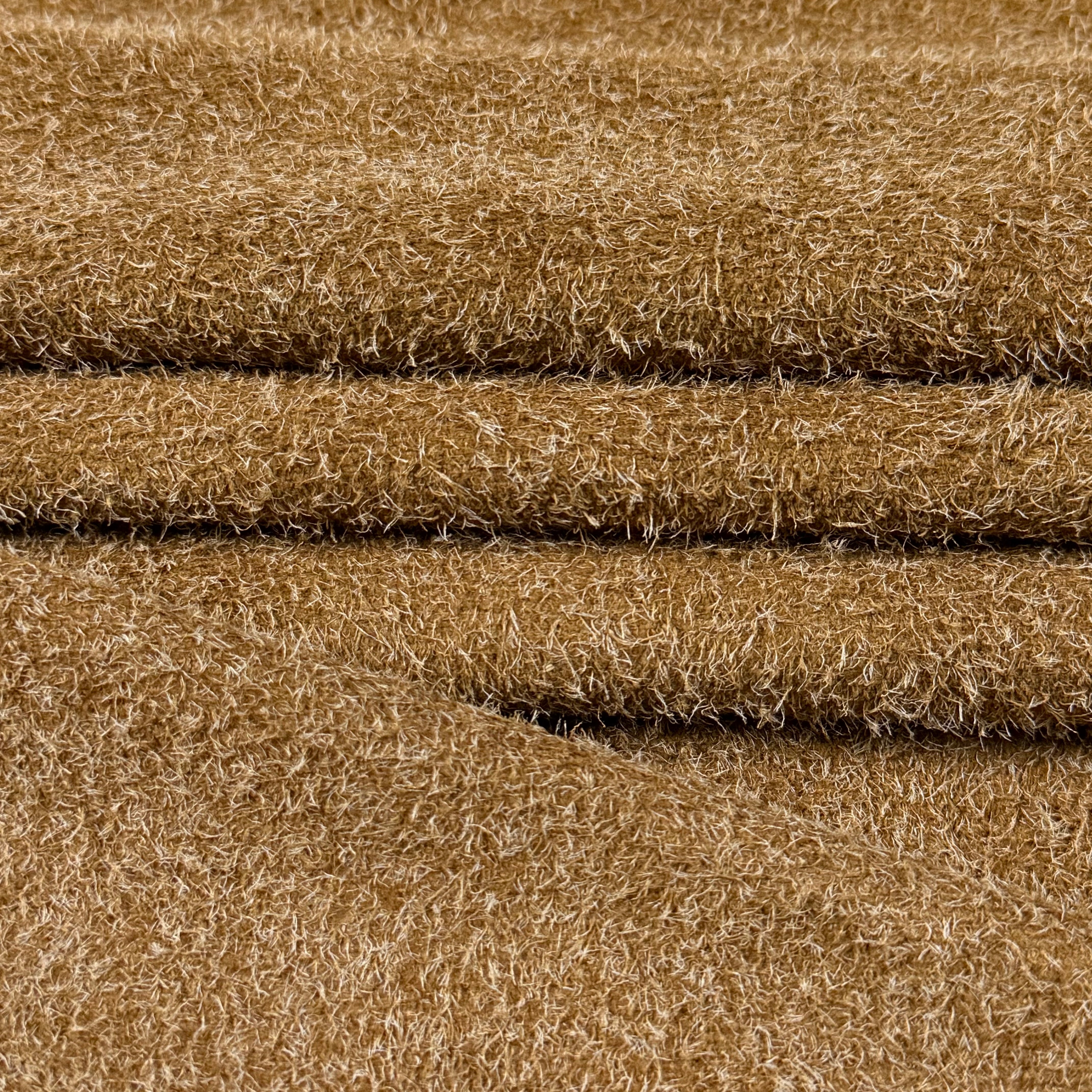Close-up of a folded Hairy Calf Suede Bend in a warm brown color, showing its shaggy, textured surface.
