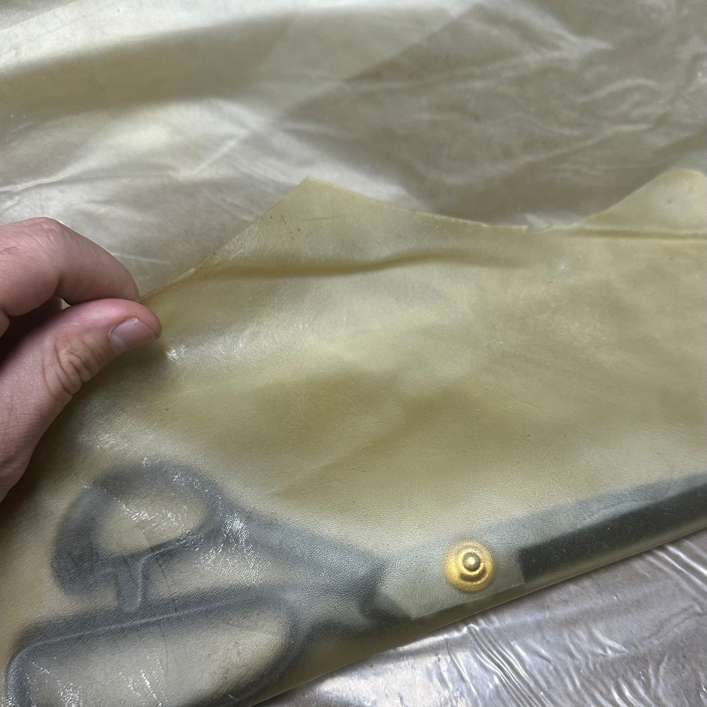 Transparent natural lamb leather, 1.5 oz, showing a thin, translucent sheet held by a hand with a visible metal snap button.