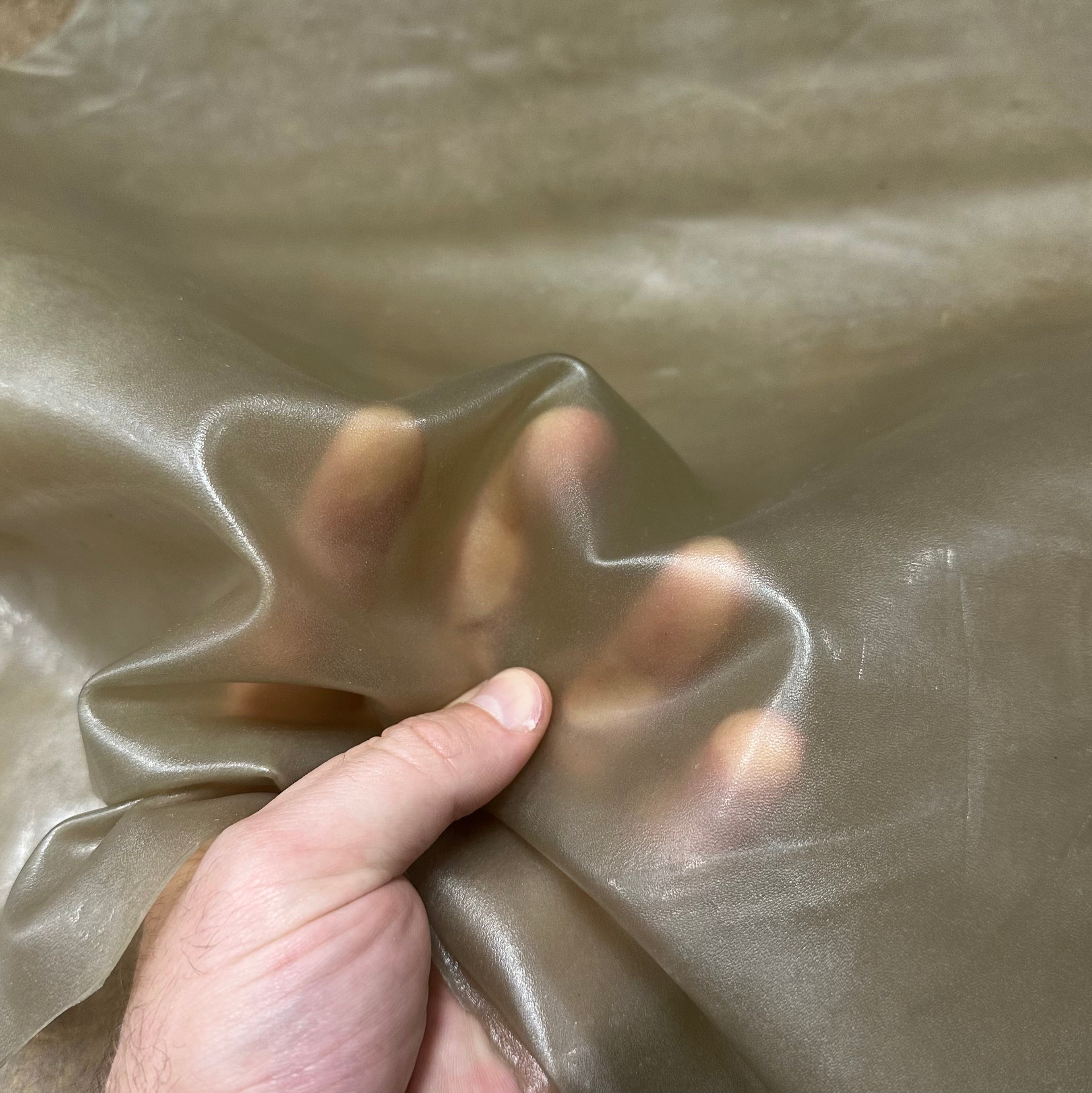 Transparent 1.5 oz lamb leather in smoke, showing a flexible, translucent material held by a hand to demonstrate texture.