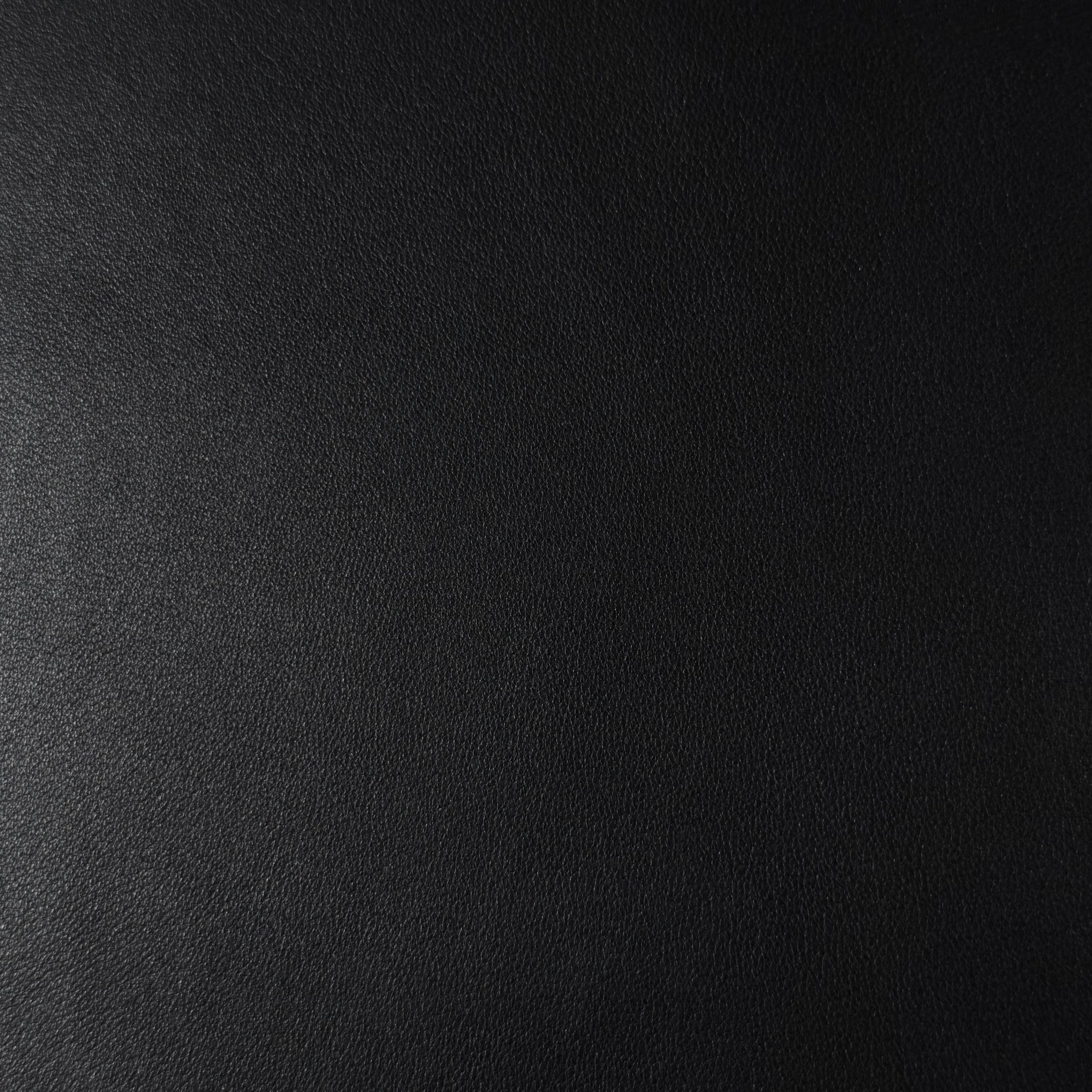 Close-up of black luxury aniline lamb nappa leather with a subtle sheen and smooth texture.