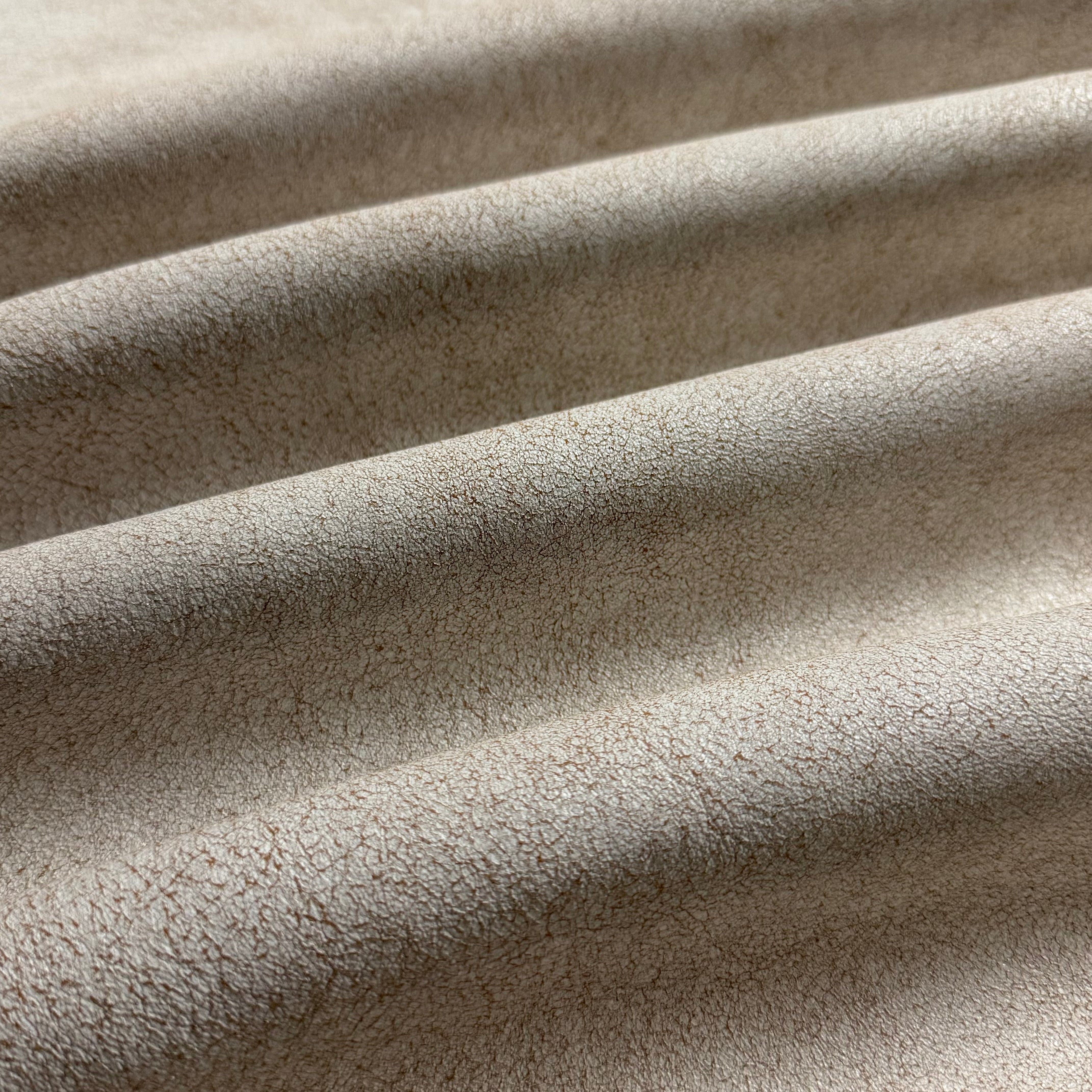 Crackle Leather in beige, featuring a textured, distressed surface with soft, draped folds in a matte finish.