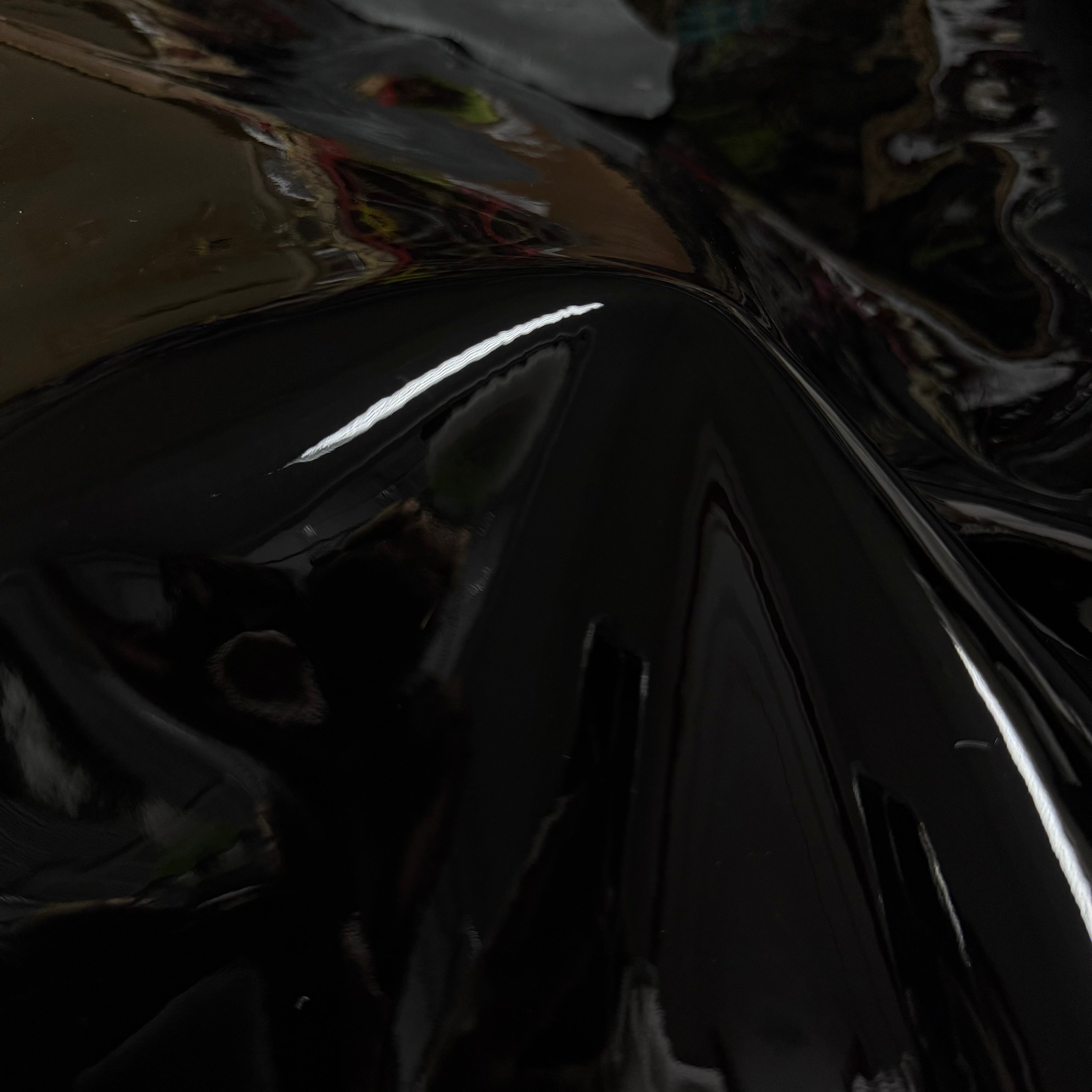Wrinkled black patent cow leather with a glossy lacquer finish and reflective surface.