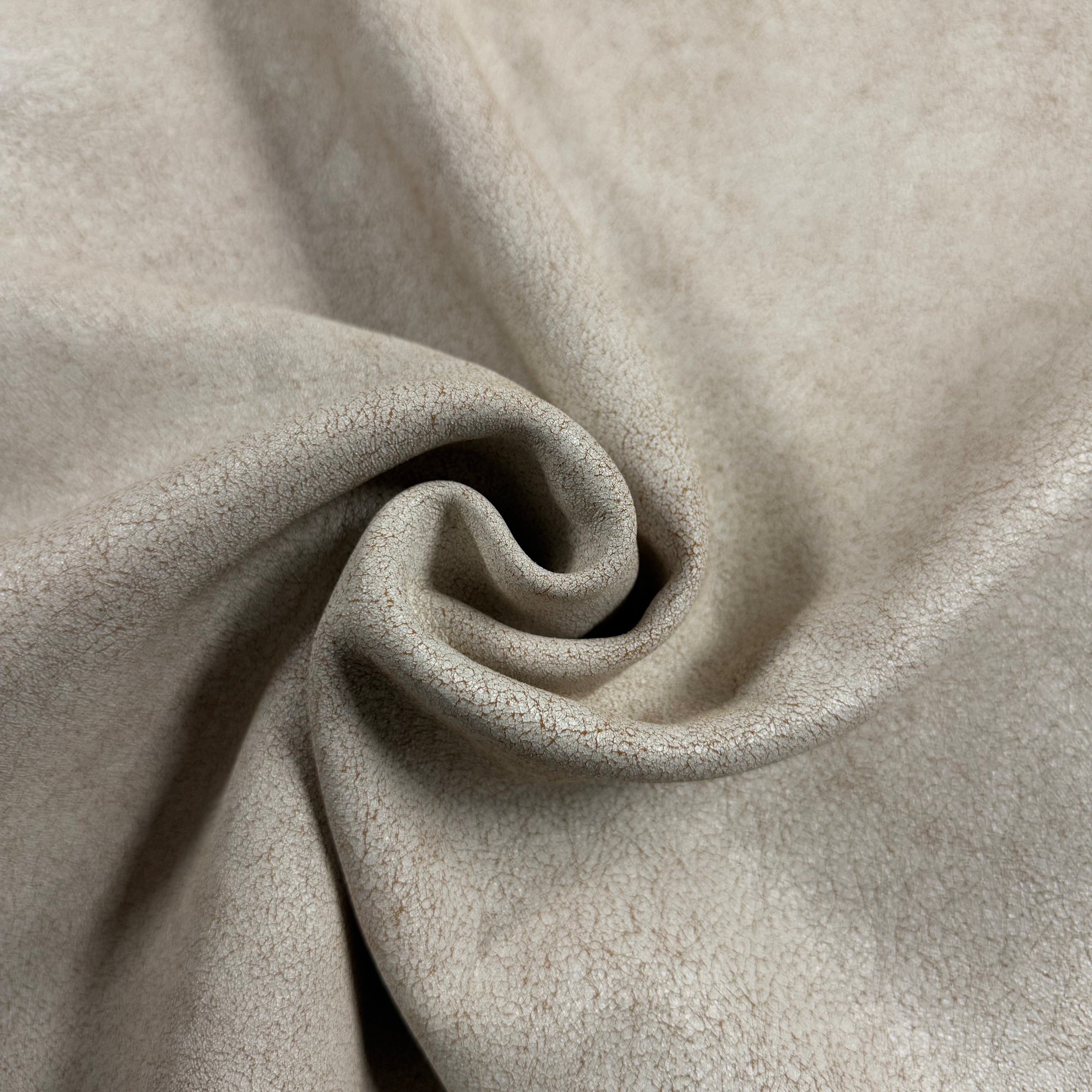 Crackle Leather in beige, featuring a soft, textured finish with a subtle distressed pattern in a draped swirl design.
