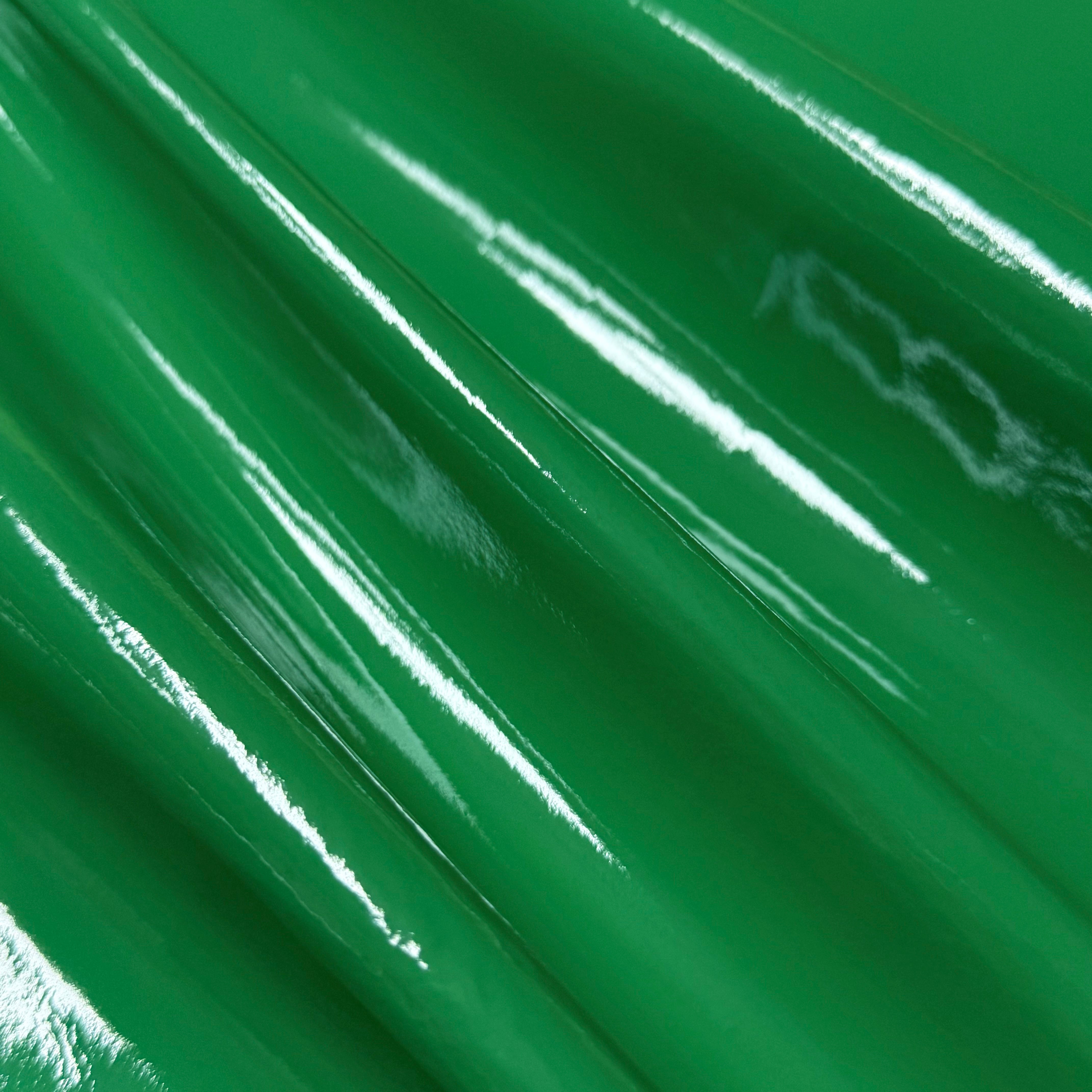 Patent Pig leather in vibrant green, featuring a high-gloss, reflective patent finish with soft, draped folds.