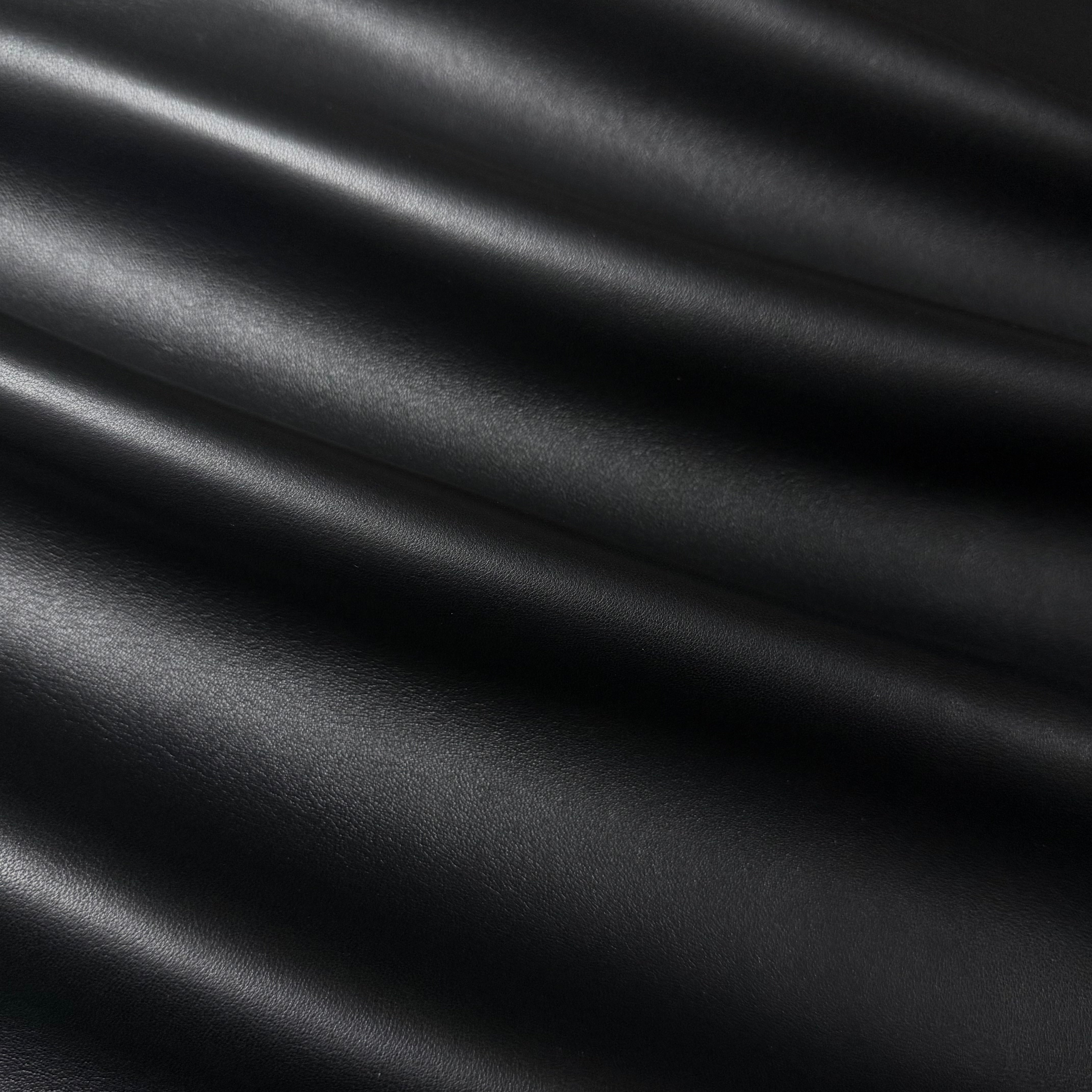Draped black luxury aniline lamb nappa leather with a subtle sheen and smooth texture.