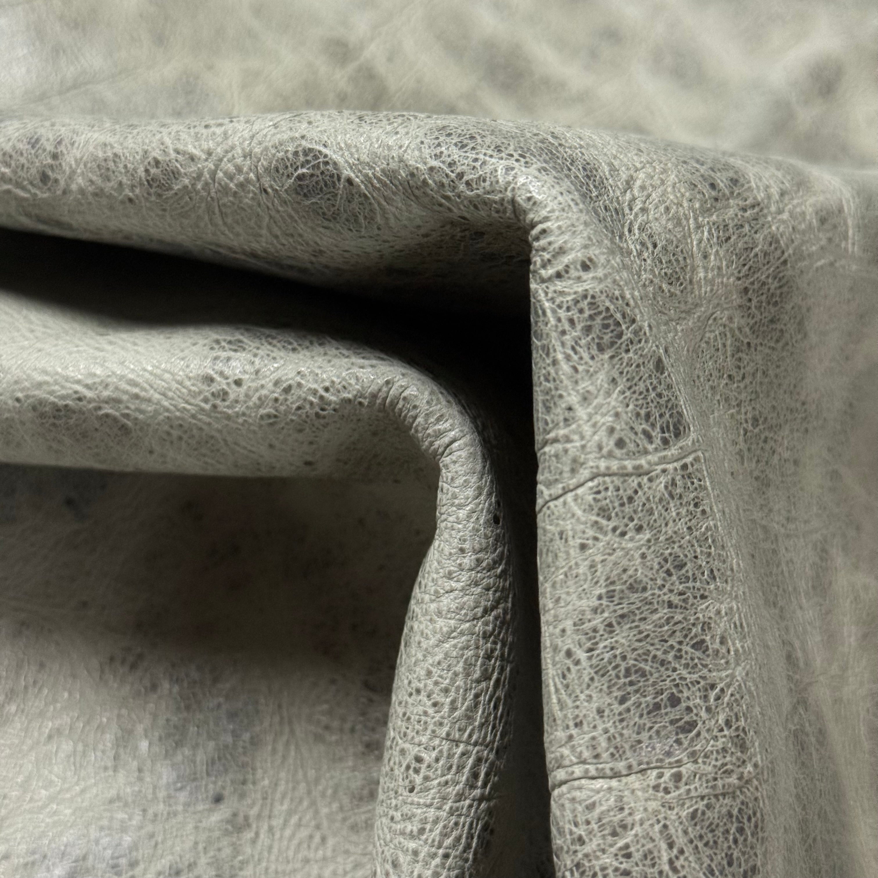 Light grey Carnauba Waxed Pull-Up Cowhide leather, 2-3 oz, featuring a distressed, textured grain and soft folds.