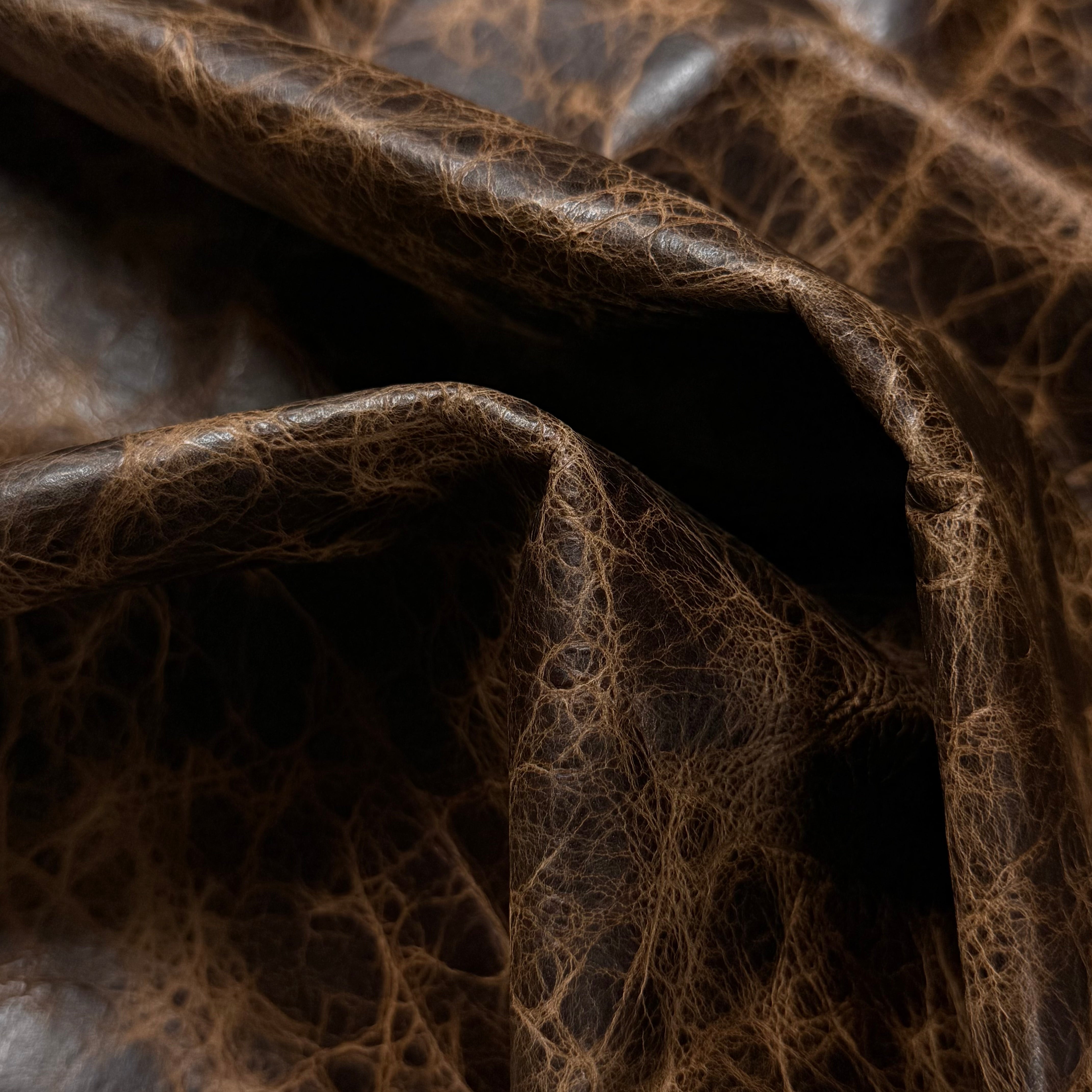 Dark brown Carnauba Waxed Pull-Up Cowhide, 2-3 oz leather with a distressed, cracked texture and natural folds.