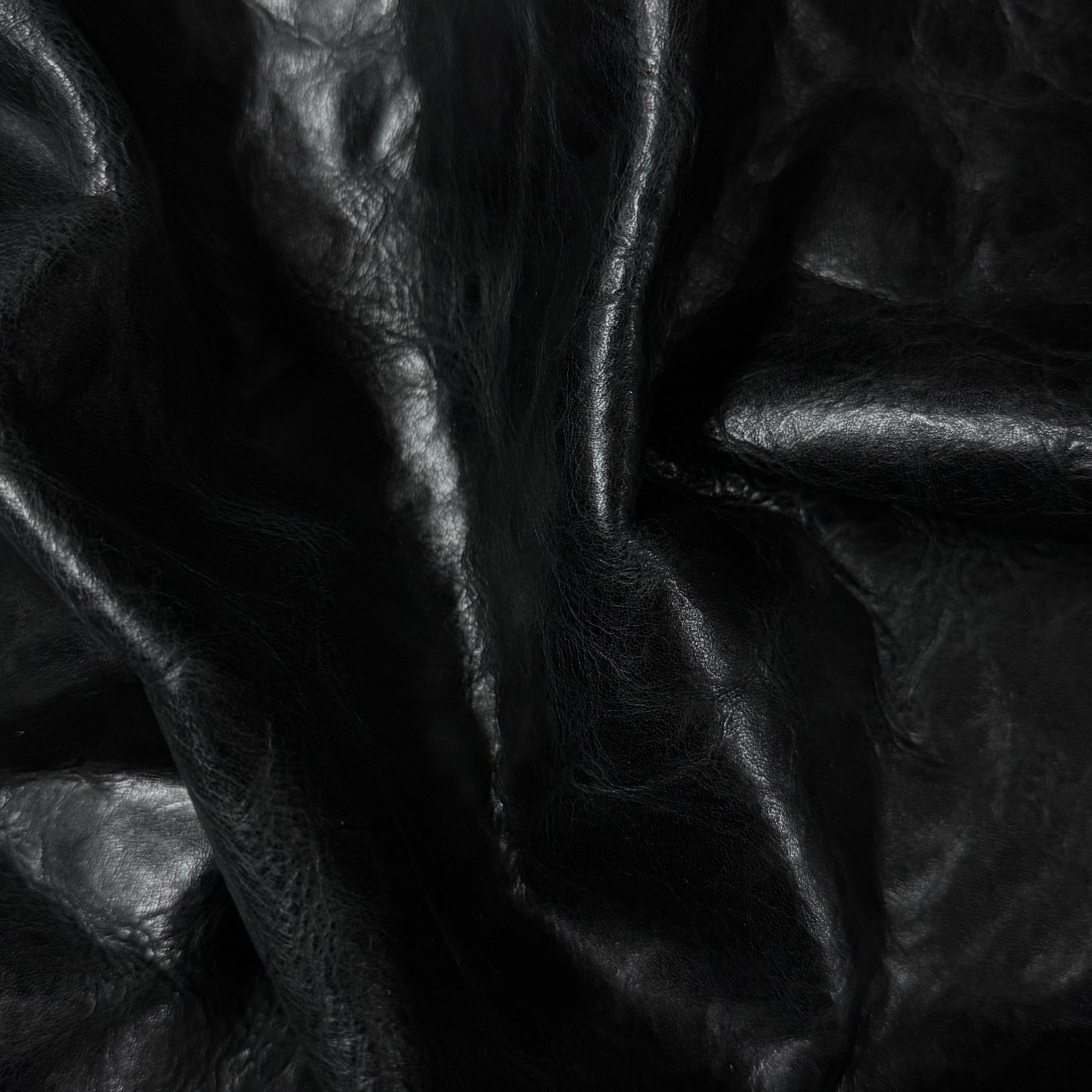 Black Carnauba Waxed Pull-Up Cowhide leather, 2-3 oz, featuring a soft, creased texture with a glossy finish.