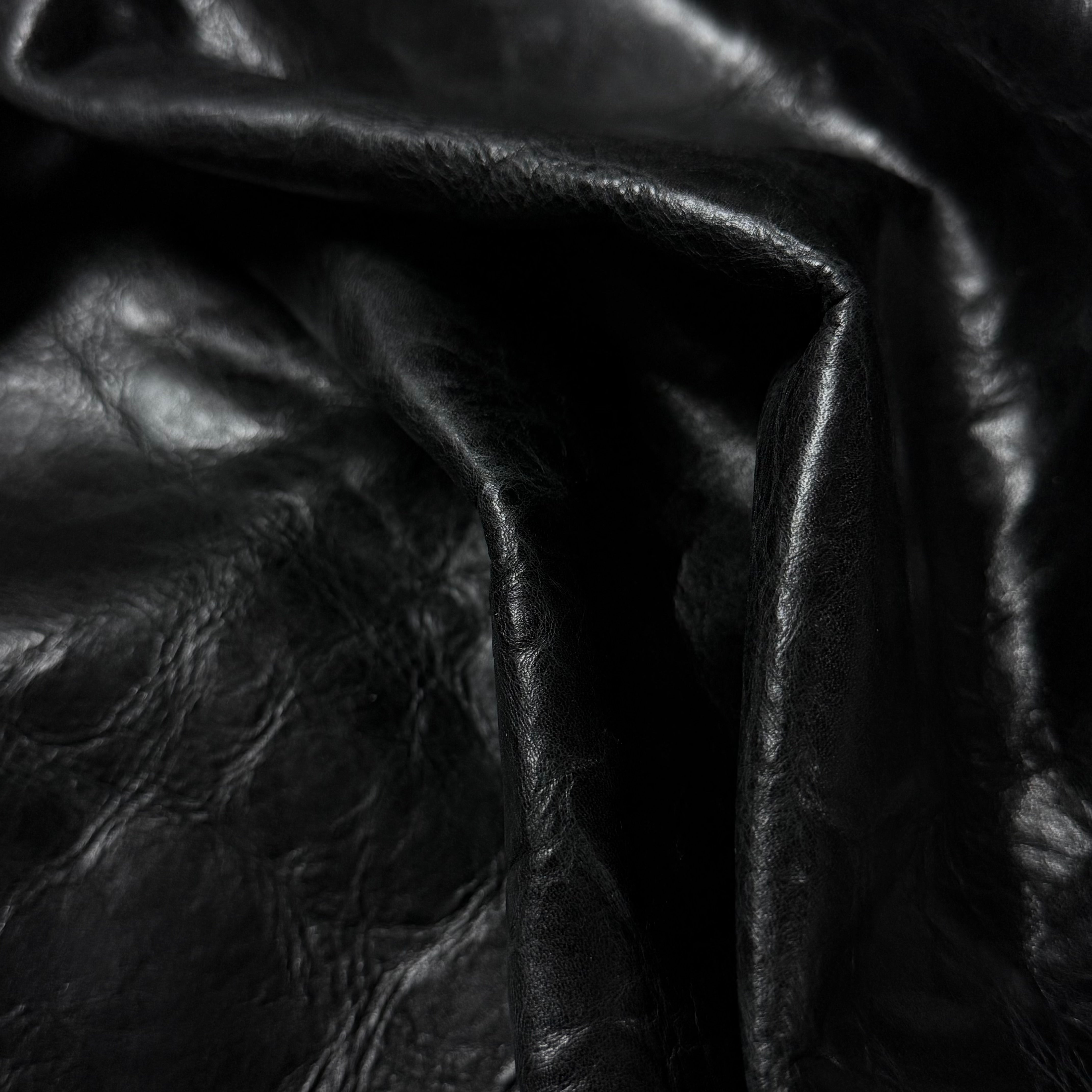 Black Carnauba Waxed Pull-Up Cowhide leather, 2-3 oz, showing a soft, creased texture and deep matte finish.