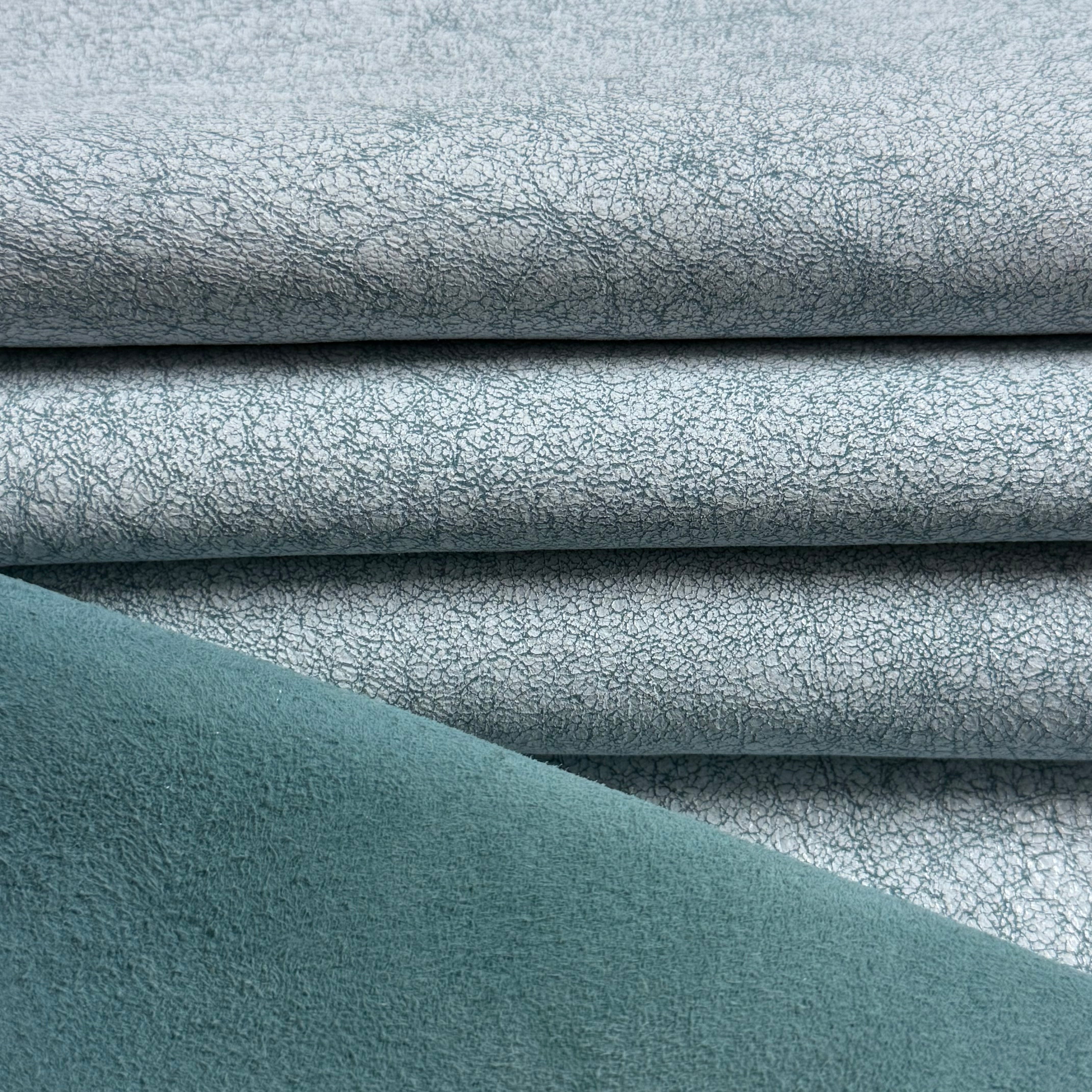Crackle Leather in blue, featuring a textured, distressed surface finish layered over a smooth, solid teal suede backing.