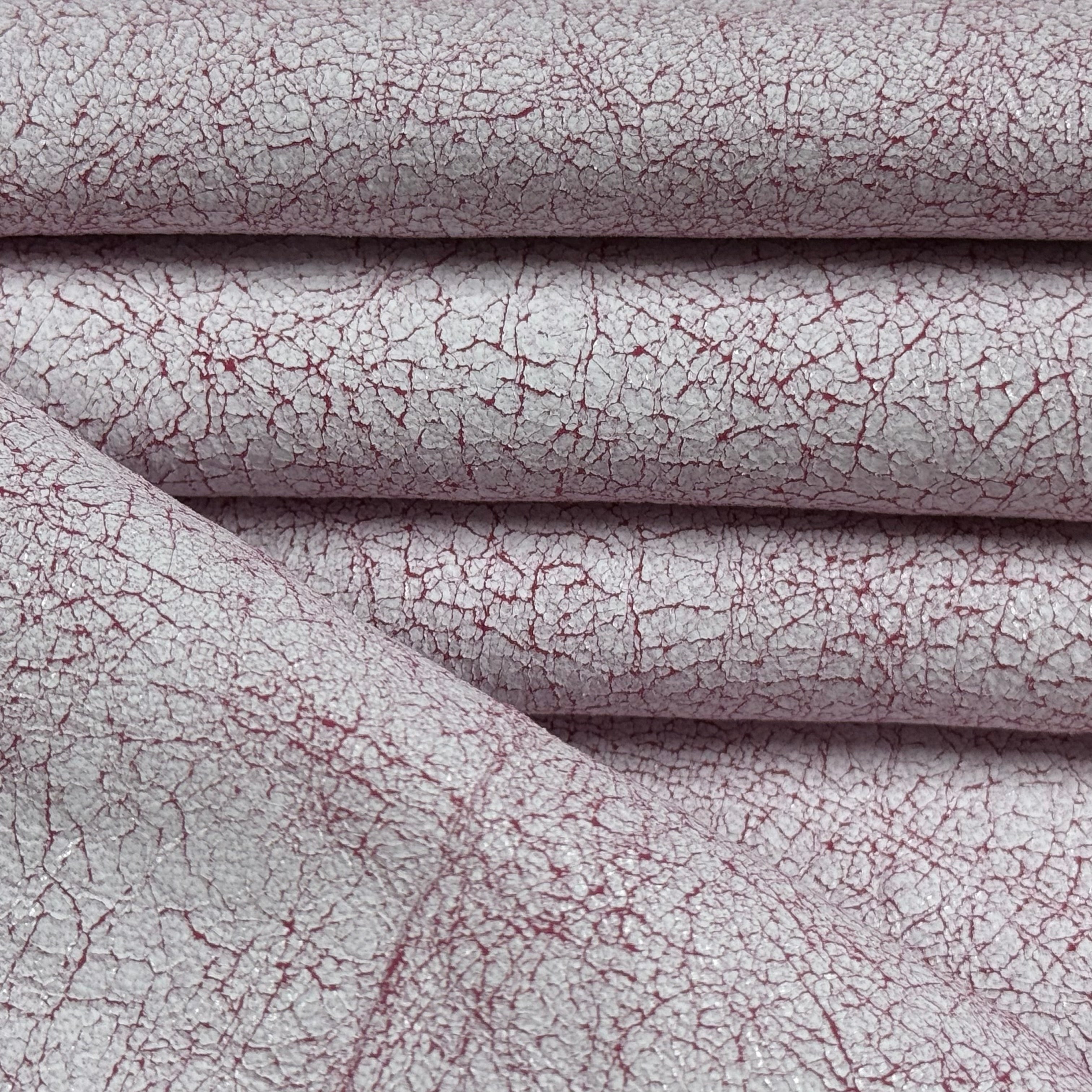 Crackle Leather fabric in burgundy and white with a distressed, textured finish folded in layers.