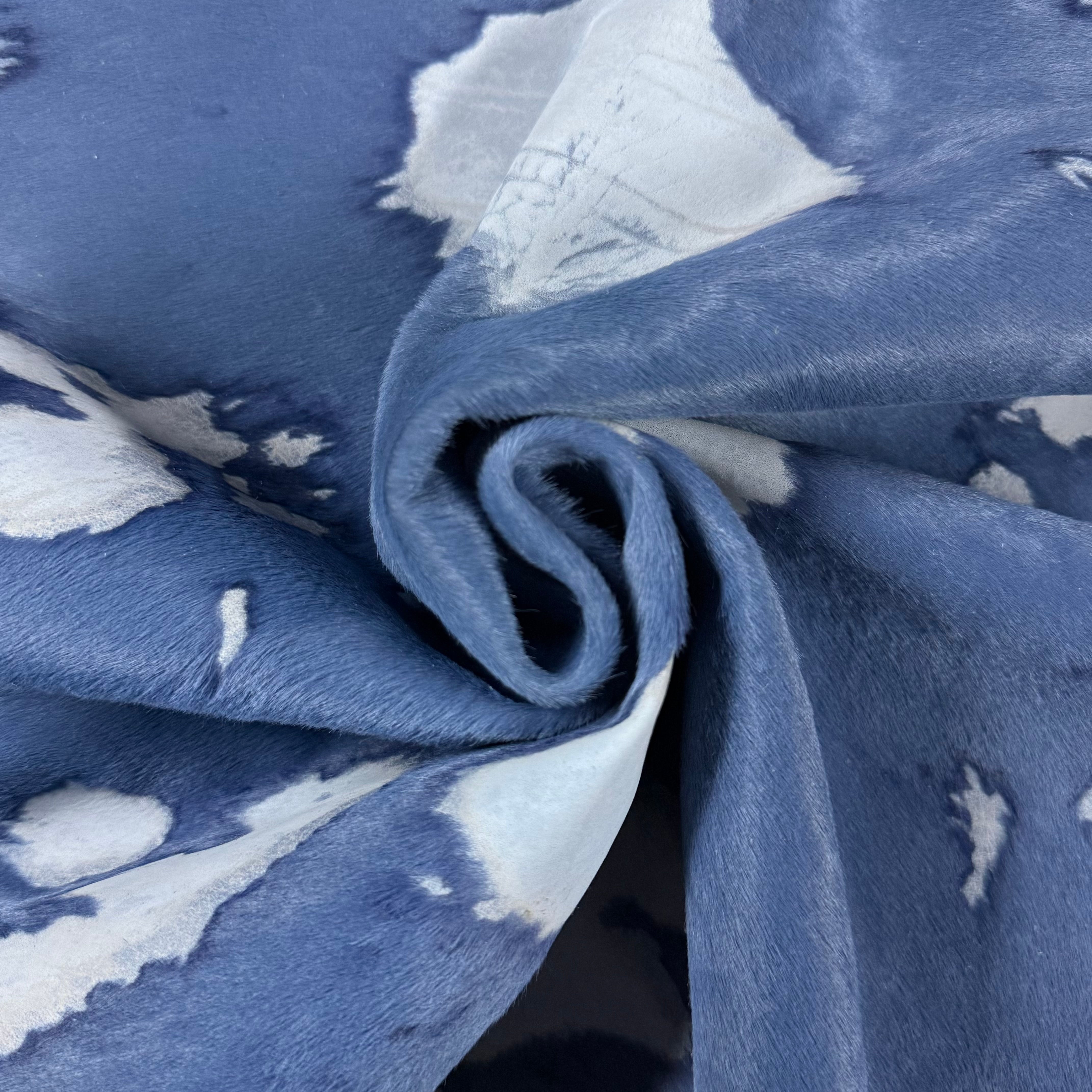Blue acid wash Cavallino hair-on calf leather with white spotting and a soft, curled texture.