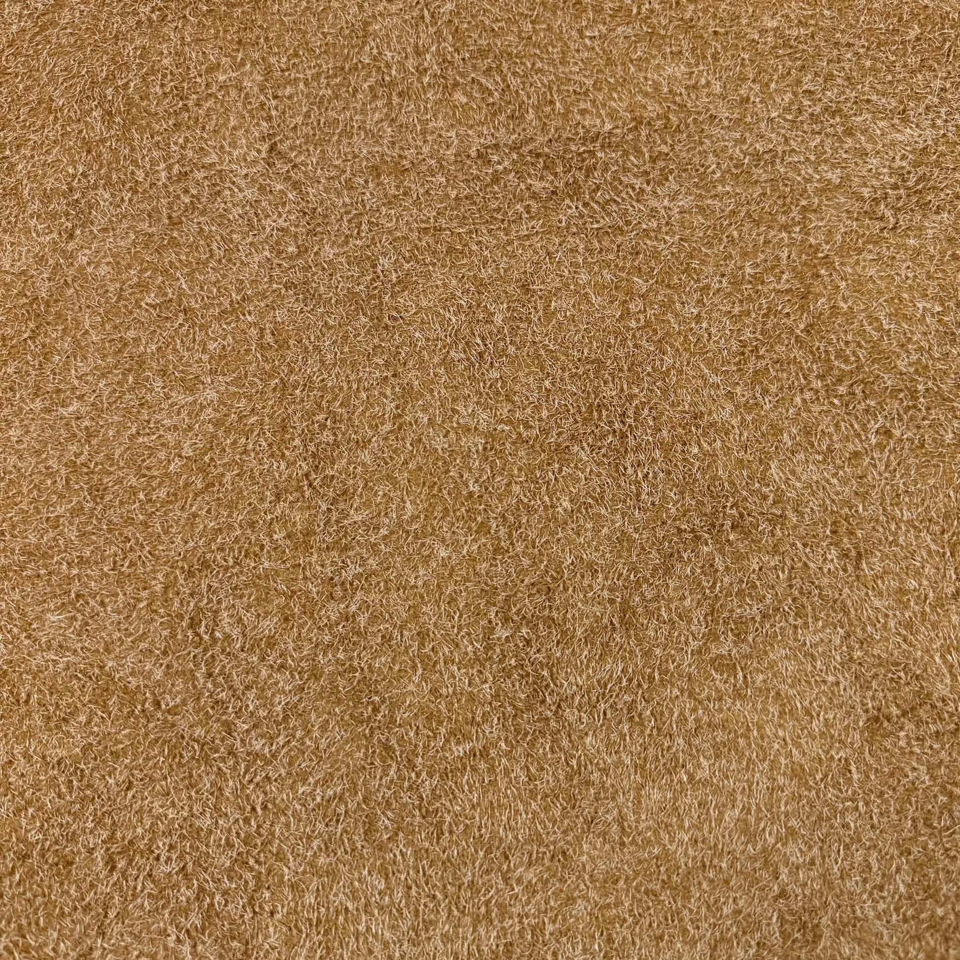 Close-up of a tan hairy calf suede leather bend with a rough-out texture and long, shaggy fibers.