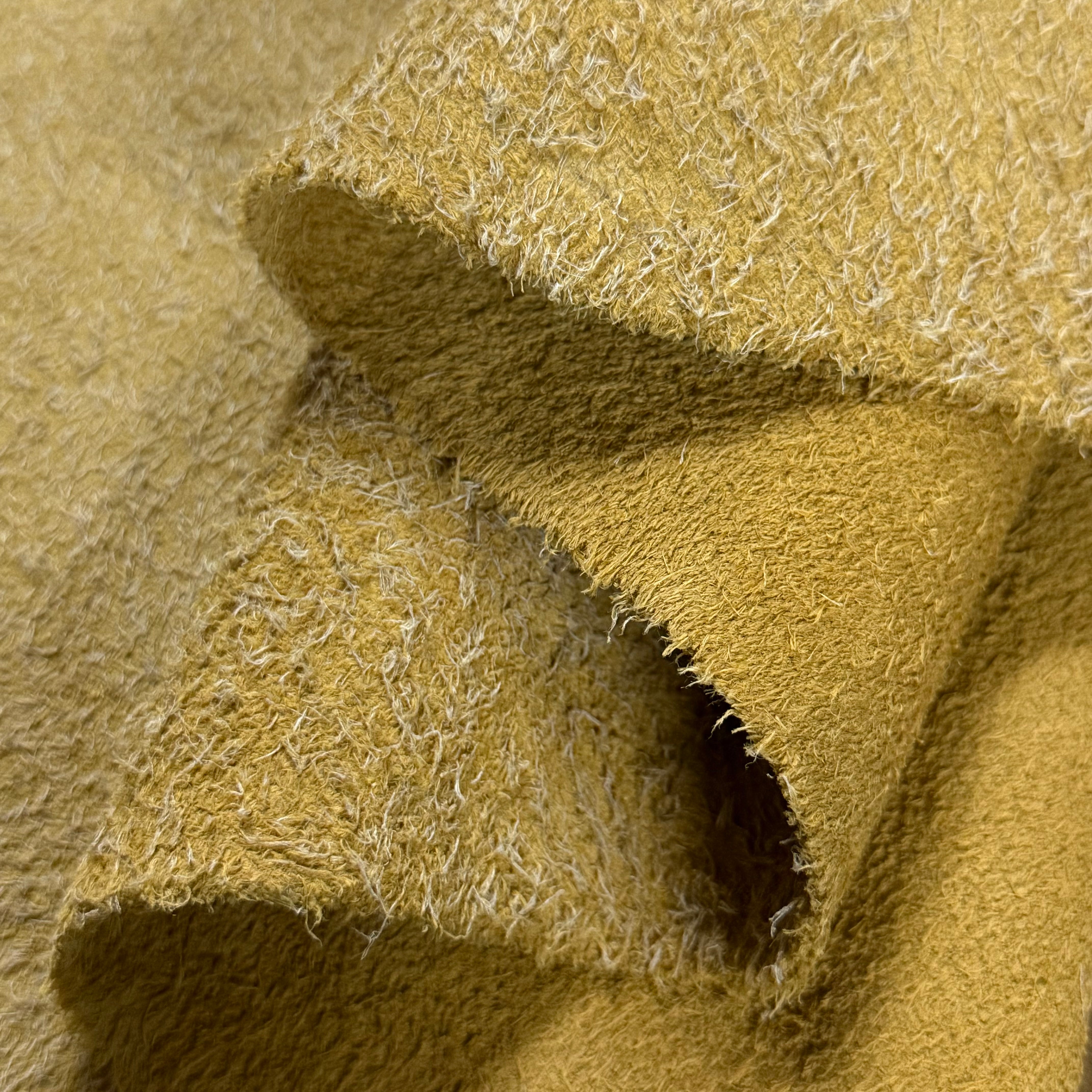 Close-up of a folded Hairy Calf Suede Bend in yellow, showing its rough-out texture with long, shaggy fibers.