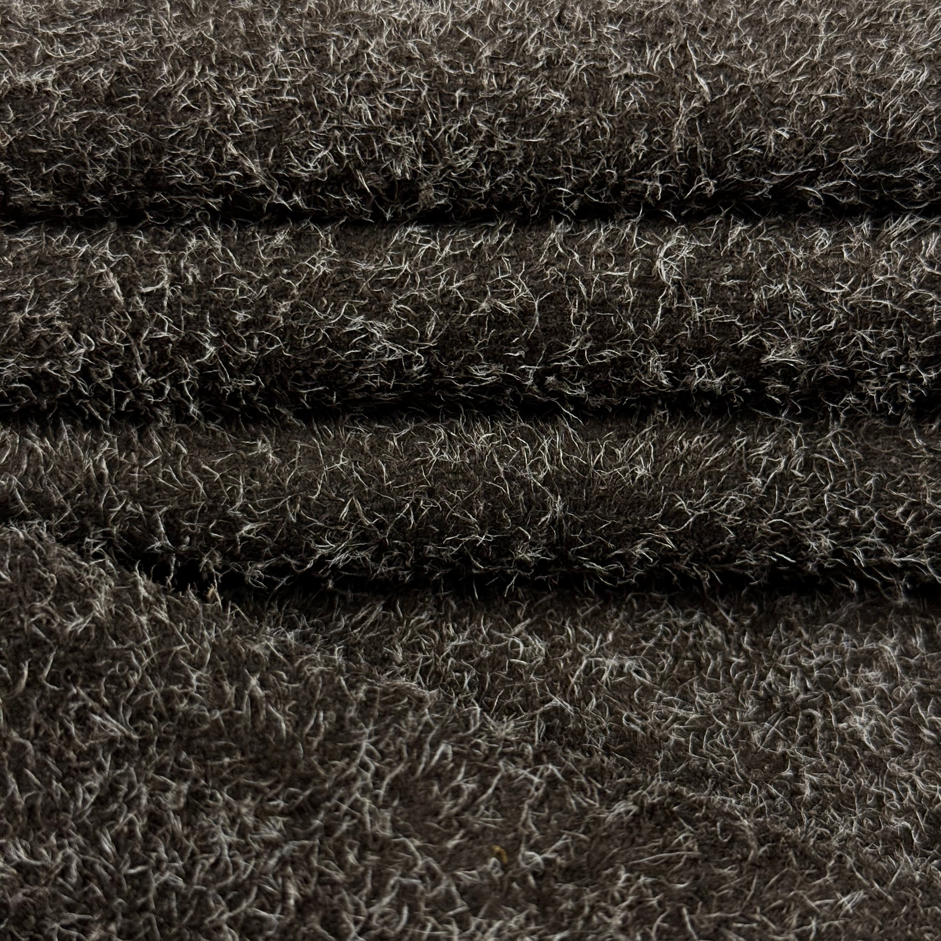 Dark brown hairy calf suede leather with contrasting long white fibers, folded.