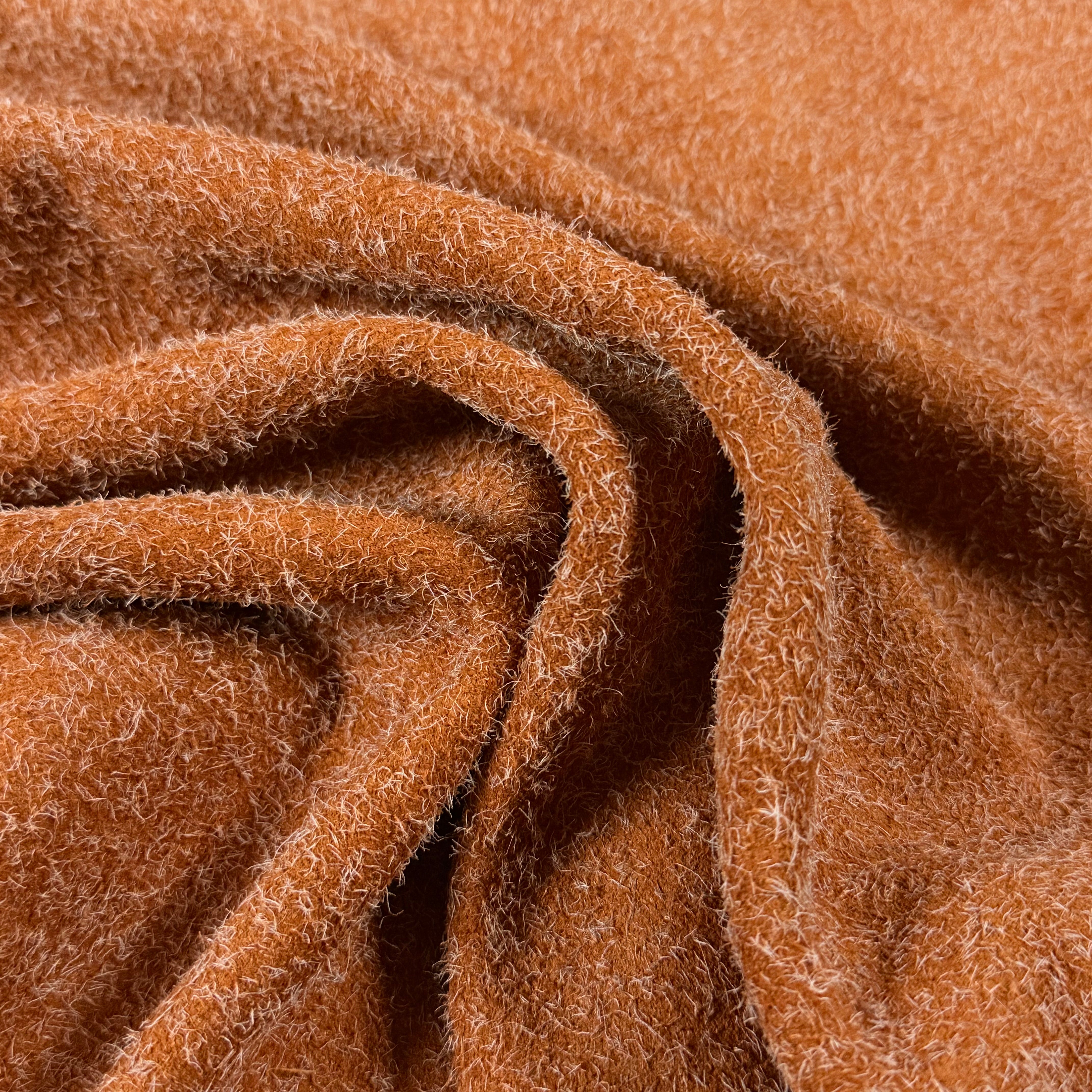 Close-up of a folded Hairy Calf Suede Bend in a rich orange-brown, showing its soft, shaggy texture.