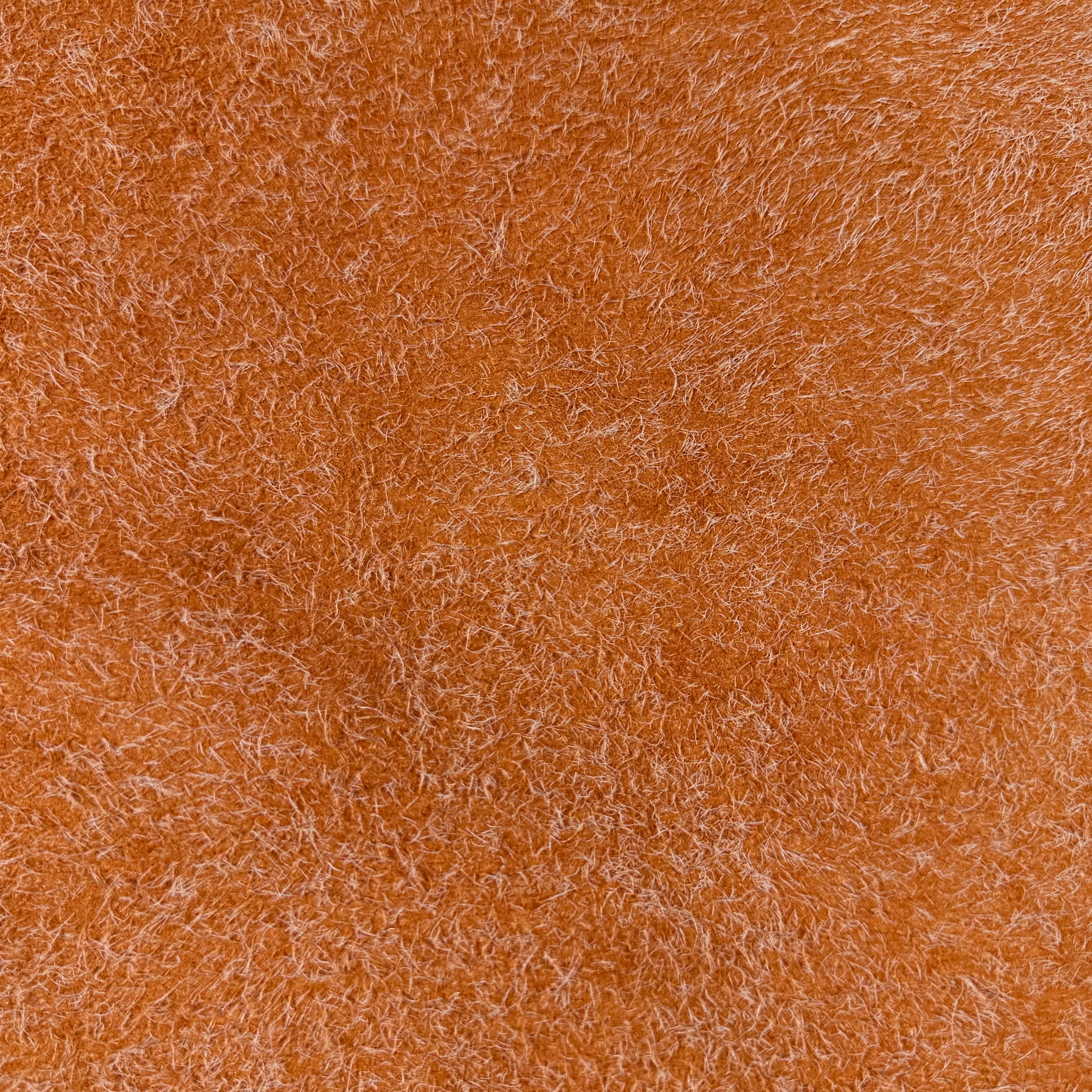 Close-up of a textured orange hairy calf suede bend with contrasting long fibers.
