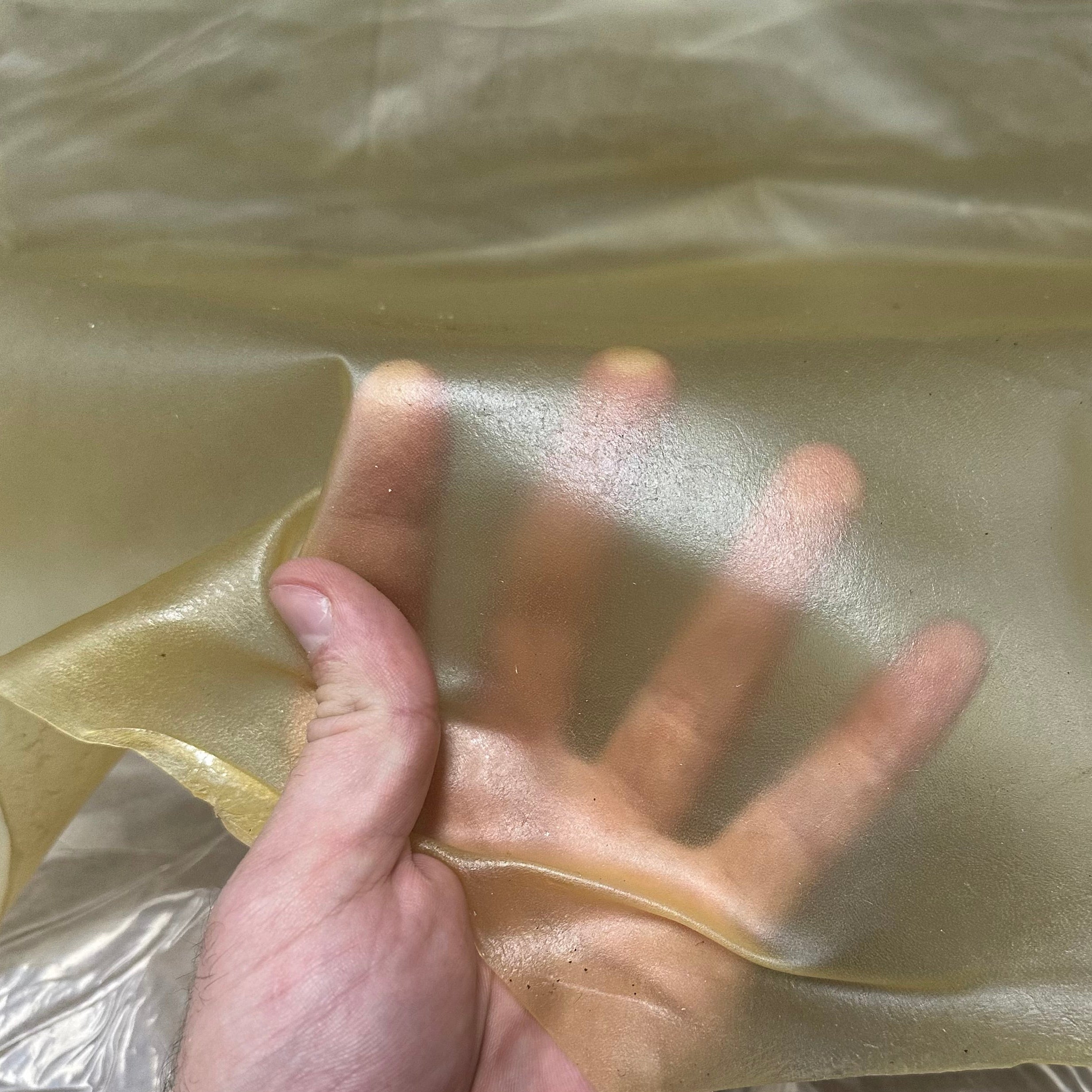 Transparent natural lamb leather, 1.5 oz, showing a thin, flexible, and translucent sheet held by a hand.
